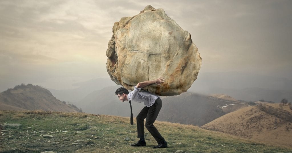 Man carrying a large stone up a mountain